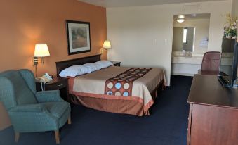 a hotel room with a large bed , a chair , and a bathroom in the background at Relax Inn