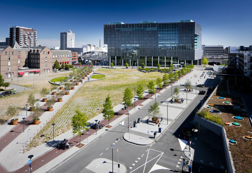 a large building with a modern design is surrounded by a modern cityscape with clear skies at Fletcher Wellness-Hotel Leiden