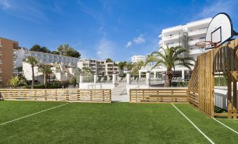 a modern apartment complex with a well - maintained green lawn , surrounded by palm trees and other greenery at Globales Palmanova