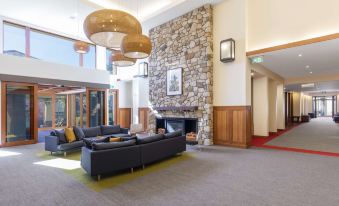 a modern living room with a fireplace , stone walls , and comfortable couches arranged around it at Yarra Valley Lodge, an EVT Hotel