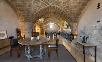 The room features tables and chairs in a rustic kitchen or living area with old stone walls at Casino Doxi Stracca by BarbarHouse