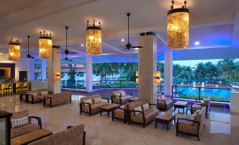 a large , well - lit room with several couches and chairs arranged in various positions , creating a comfortable seating area at Holiday Inn Resort Goa