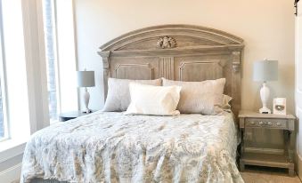 a well - decorated bedroom with a wooden bed , two nightstands , and a lamp , along with a window on the right side at Inn on Central