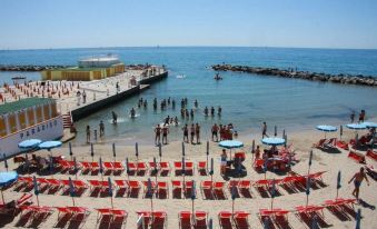 a beach scene with a pier and umbrellas , where people are enjoying the water and sand at Hotel Rio Sanremo
