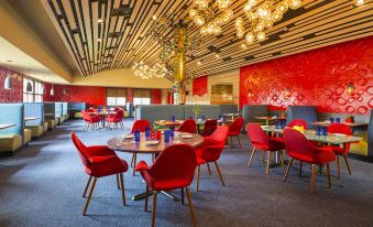 a modern restaurant with red chairs and tables , a chandelier hanging from the ceiling , and a red wall at Four Points by Sheraton Chicago O'Hare