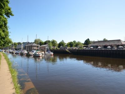 a river with several boats docked along the banks , creating a picturesque scene on a sunny day at Kim