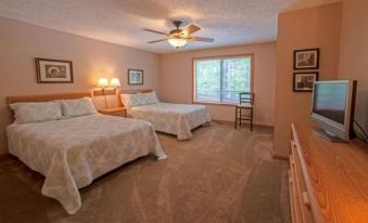 a well - lit bedroom with two beds , nightstands , and a window , as well as a view of the outdoors through large windows at Agaming Golf Resort