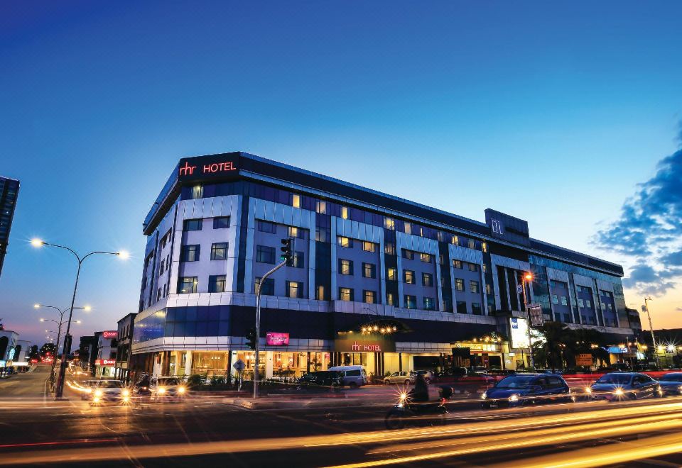 a large hotel building located on a busy city street , with cars and traffic passing by at RHR Hotel Kajang
