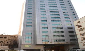 A large building with cars parked in front and an office block on the other side at Fajr Al Badea 5