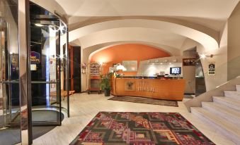 a hotel lobby with an orange reception desk , a couch , and a rug on the floor at Phi Hotel Principe