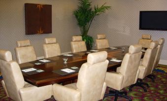 a conference room with a large wooden table , beige chairs , and a plant in the corner at GreenLinks Golf Villas at Lely Resort