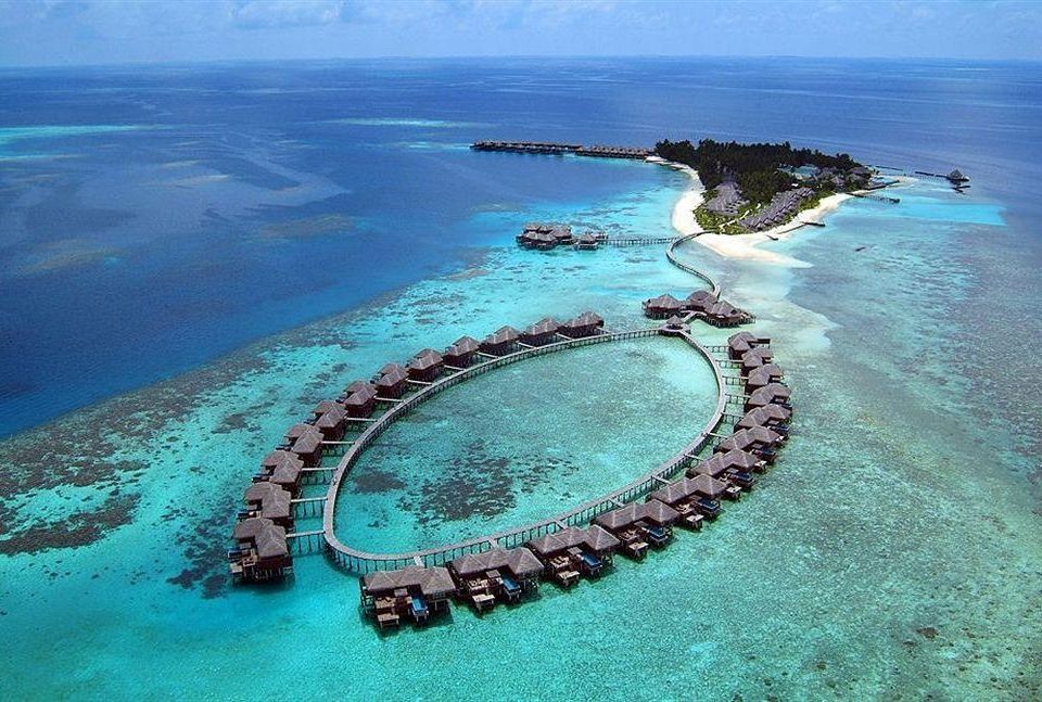 aerial view of a tropical island with overwater bungalows and a circle of umbrellas on the sandy shore at Coco Bodu Hithi