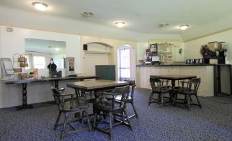 a dining room with a table and chairs , as well as a kitchen area with various appliances at Colony Motel Jamestown