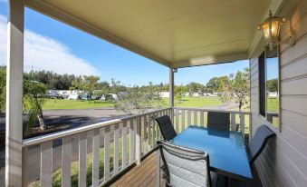 a wooden deck with a table and chairs , surrounded by a covered area with a railing at Discovery Parks - Eden