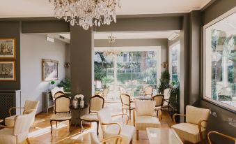 a large room with wooden floors and chairs , a chandelier hanging from the ceiling , and large windows at Hotel Metropole