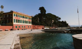 a large building with a red and green facade is situated next to the ocean at Hotel Metropole