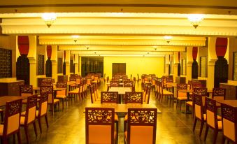 The large dining area of a restaurant, furnished with wooden tables and chairs, is currently vacant for the first time at Sayeman Beach Resort