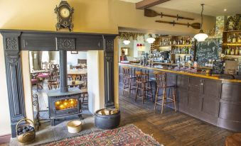 a cozy bar area with a fireplace , bar stools , and a wooden bar , creating a warm and inviting atmosphere at The Cuckoo Brow Inn