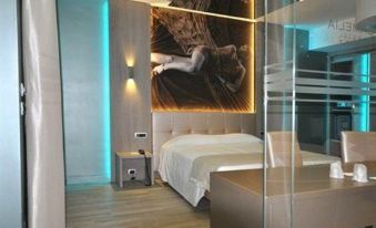 a modern bedroom with a large bed and a glass partition separating the sleeping area from the rest of the room at Hotel Camelia