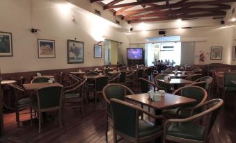 a restaurant with wooden tables and chairs , a tv on the wall , and framed pictures at Plaza Hotel