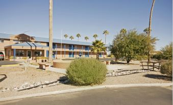 a building with a blue roof and balconies is surrounded by trees and bushes , located in an urban setting at Americas Best Value Inn Eloy/Casa Grande