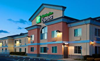 a holiday inn express hotel with its logo lit up against the night sky , and the building has a large sign above the entrance at Holiday Inn Express & Suites Jackson