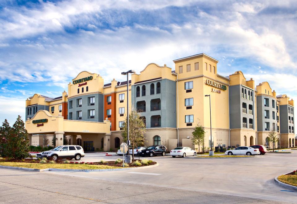 a large , modern hotel building with a well - lit exterior and a parking lot in front at Courtyard Houma