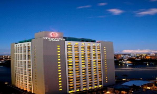 "a tall , modern hotel building lit up at night with the word "" yuya "" on its sign" at Stamford Plaza Brisbane