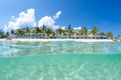 a beach scene with a hotel in the background and clear blue water in the foreground at Wyndham Reef Resort Grand Cayman