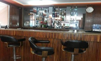 a bar with wooden walls and black stools , a counter filled with various bottles of alcohol at Hotel Westwood