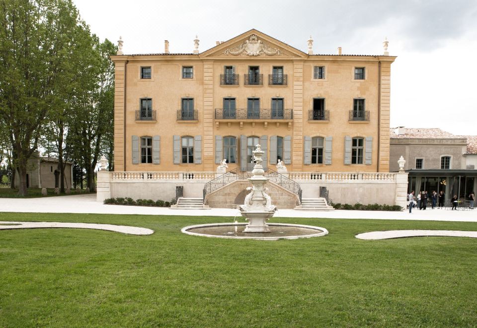 a large stone building with a fountain in front of it , surrounded by a grassy yard at Chateau de Fonscolombe