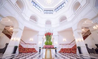 a grand white marble staircase with red stairs , and a vase of flowers in the middle of the stairs at Rizal Park Hotel