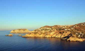 a scenic view of a rocky coastline with houses and buildings on the cliffs , under a clear blue sky at Amazona