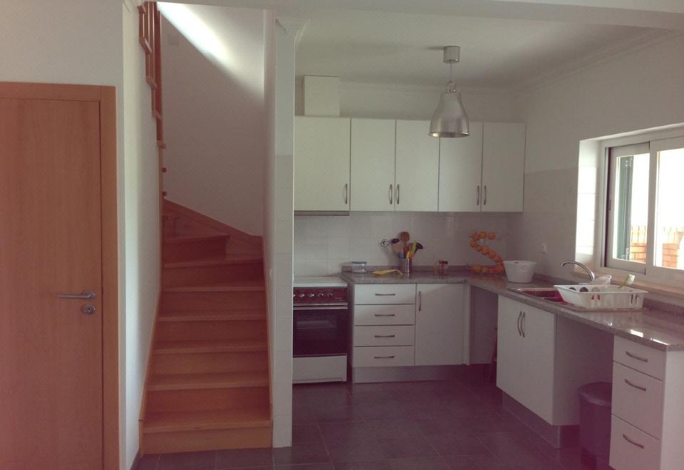 a kitchen with white cabinets , a stove , and a staircase leading to the second floor at Casa do Rio