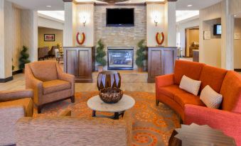 a spacious living room with a large flat - screen tv mounted on the wall , surrounded by comfortable couches and chairs at Homewood Suites by Hilton Dover
