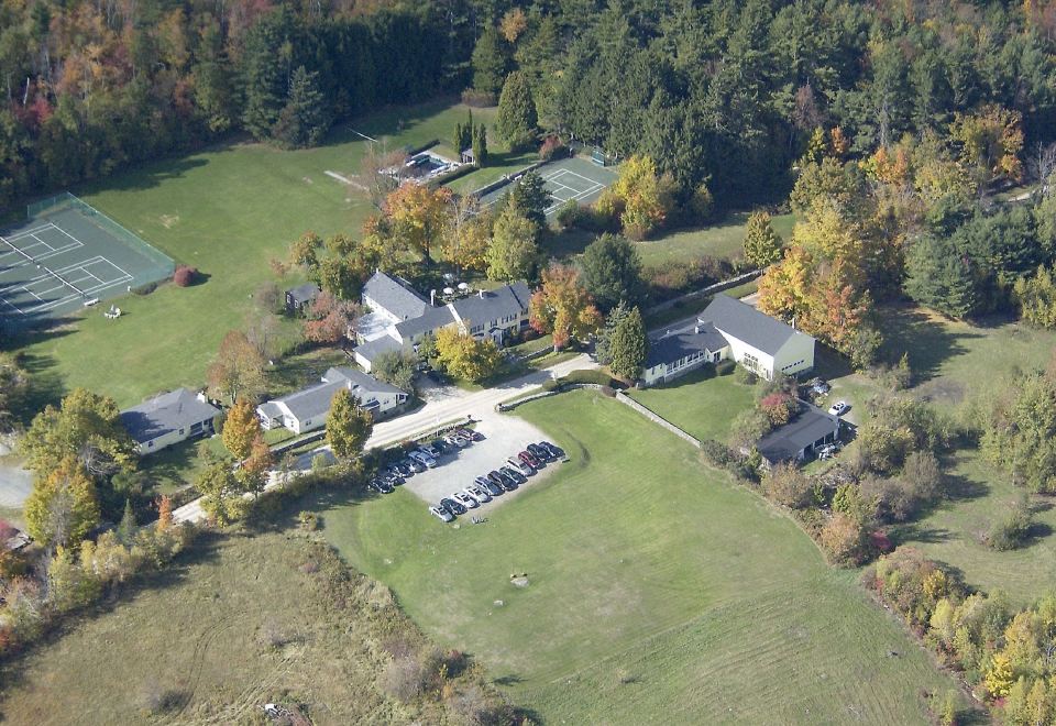 aerial view of a large grassy field with multiple buildings and trees , surrounded by hills at Dexter's Inn