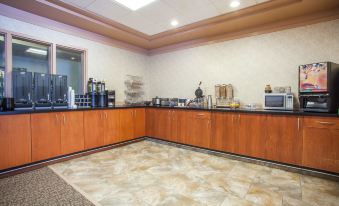 a breakfast bar with a variety of food and drinks , including coffee , juice , and pastries at Ramada by Wyndham Estevan