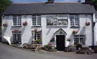 the exterior of a white building with a sign above the door and various flower arrangements on the front at The Who'd Have Thought It Inn