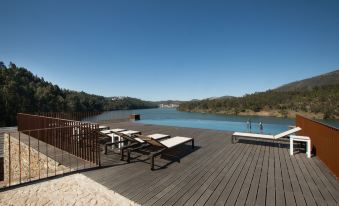 a large wooden deck overlooking a body of water , with several lounge chairs placed around it at Octant Douro