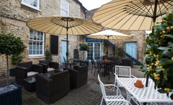 an outdoor dining area with several tables and chairs , surrounded by umbrellas and a building at The Blue Boar