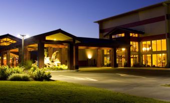 a large wooden building with a lit entrance and a statue of a man at Blue Lake Casino and Hotel
