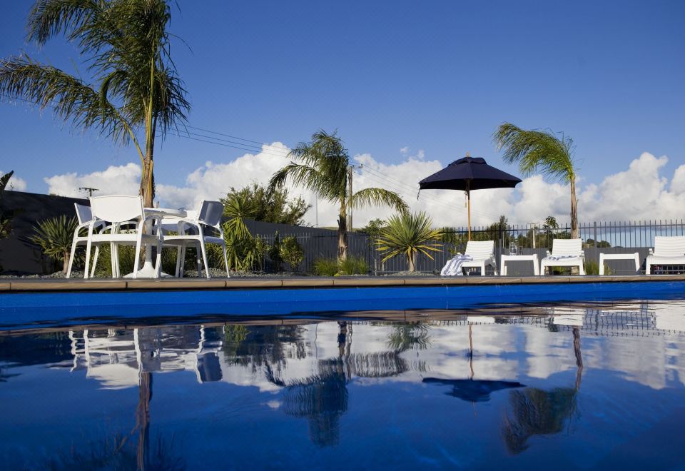 a large swimming pool with palm trees and lounge chairs surrounding it , creating a relaxing atmosphere at Motel Oasis