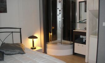 a bedroom with a bed , a bathroom with a bathtub , and a lamp on the nightstand at Les Flots Bleus