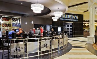 a group of people are standing in a restaurant with a large chandelier and black and white checkered floor at Saratoga Casino Hotel