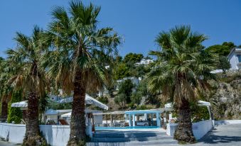 a white building with palm trees and a blue building , situated on a hill overlooking the ocean at Belvedere Hotel