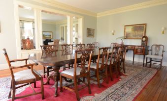 a large dining room with a wooden table and chairs , surrounded by white columns and blue walls at Woodville Bed and Breakfast