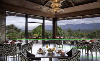 a dining area with a zebra print table and chairs , surrounded by windows offering a view of the outdoors at The Serai Bandipur