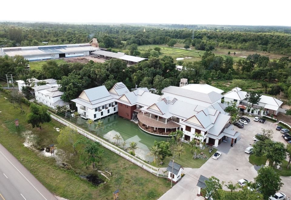 a large , modern building with a white roof and gray walls is surrounded by green trees and a gray path at Nonghan Grand Hotel and Resort