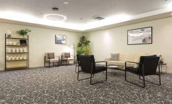 a modern waiting room with comfortable seating , a coffee table , and framed art on the wall at Sage Hotel Wollongong