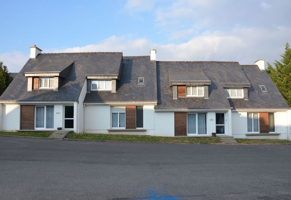 a large house with a row of houses on the side , located on a street at Logis Golfe Hotel